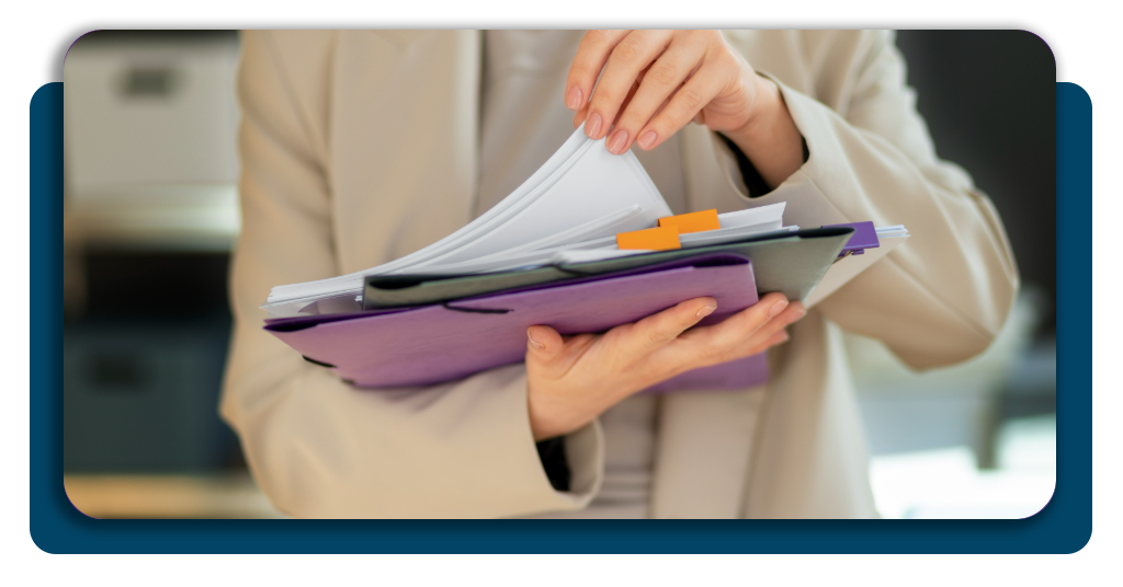 A close-up of a person organizing medical and financial papers into a neat, labeled accordion folder on a clean desk
